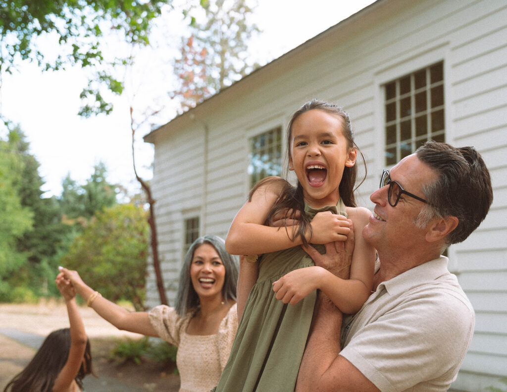 Father holding his daughter as she laughs joyfully during a candid Orange County family photo session.