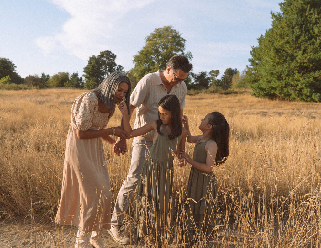 Family of four walking through tall grass during golden hour in Irvine, captured by an Orange County family photographer.
