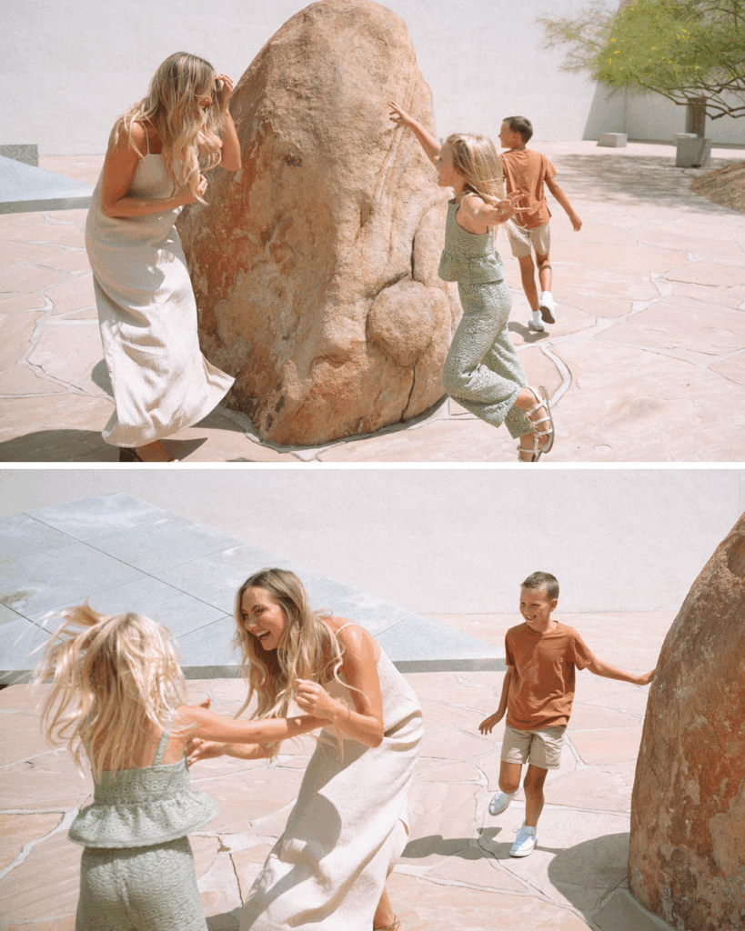 Mother and children laughing and playing a game of chase near the large stone sculptures at Noguchi Garden in Costa Mesa.