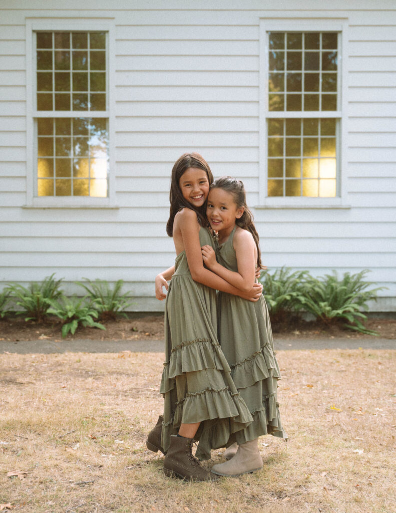 Two sisters hugging each other in matching fall outfits during family photos in Irvine, California.