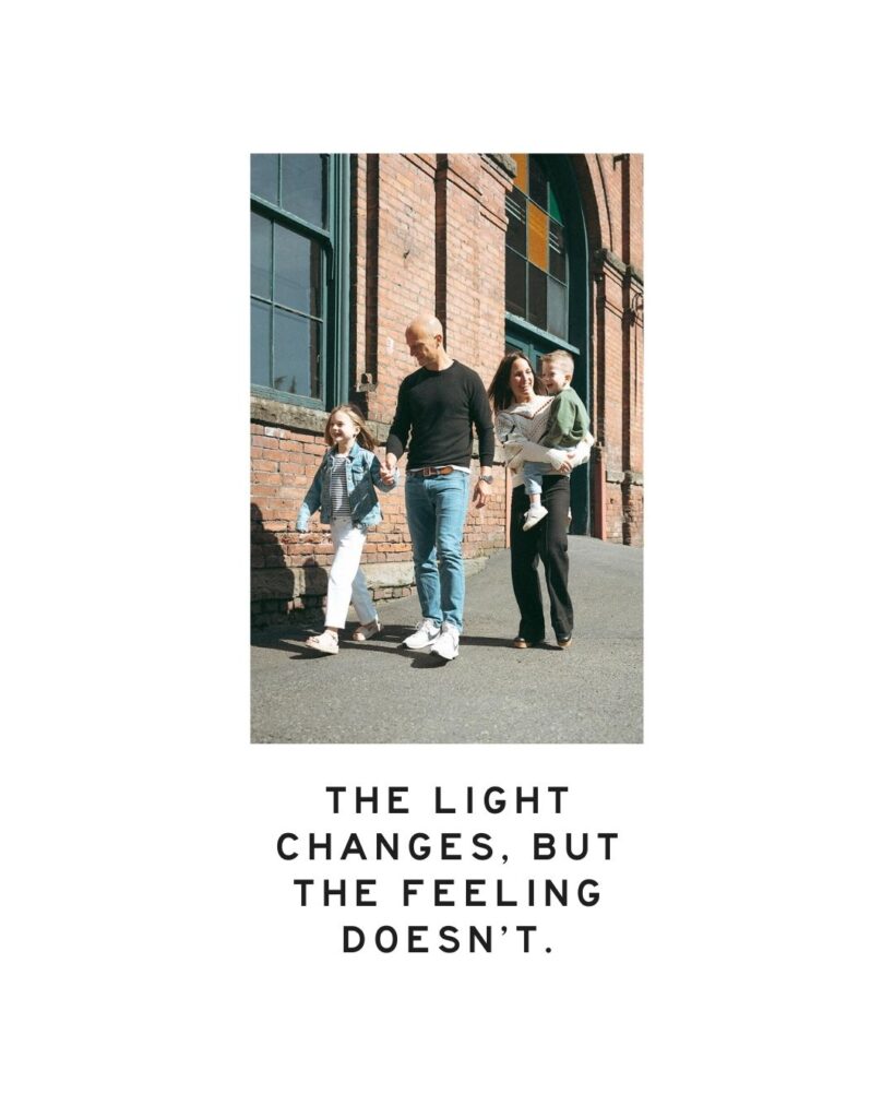 Family walking together by a brick wall in natural sunlight, with text overlay: “The light changes, but the feeling doesn’t.” Orange County family photographer session image.