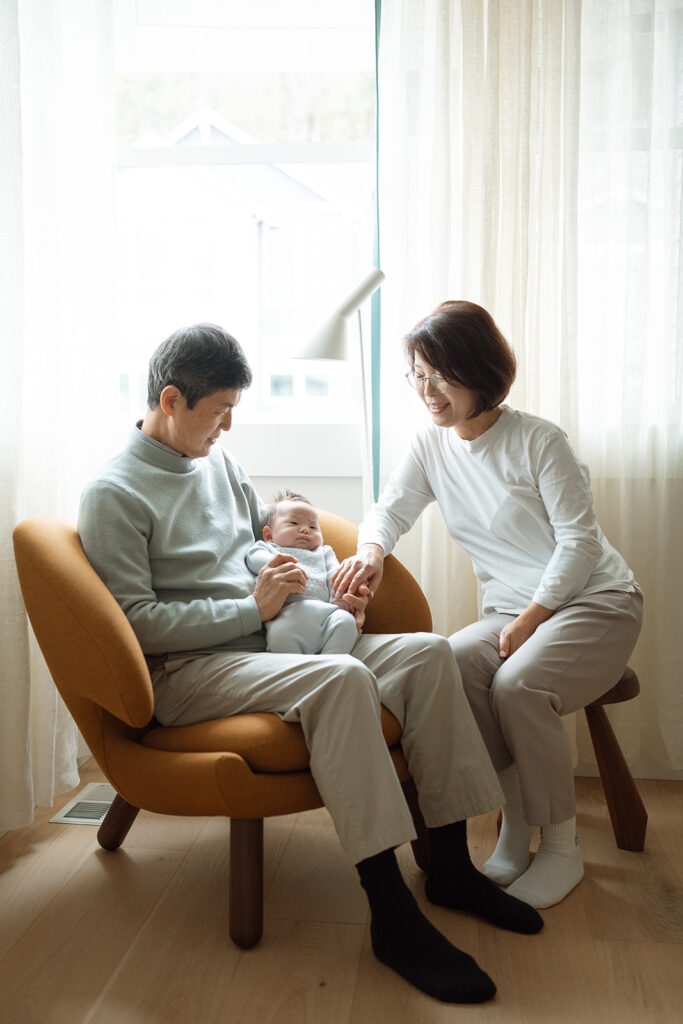 Grandparents holding newborn baby in cozy living room during a multigenerational in-home photography session in Orange County.