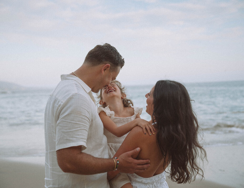 Family laughing together at the beach in Laguna Beach, photographed by Maria Alcantara.