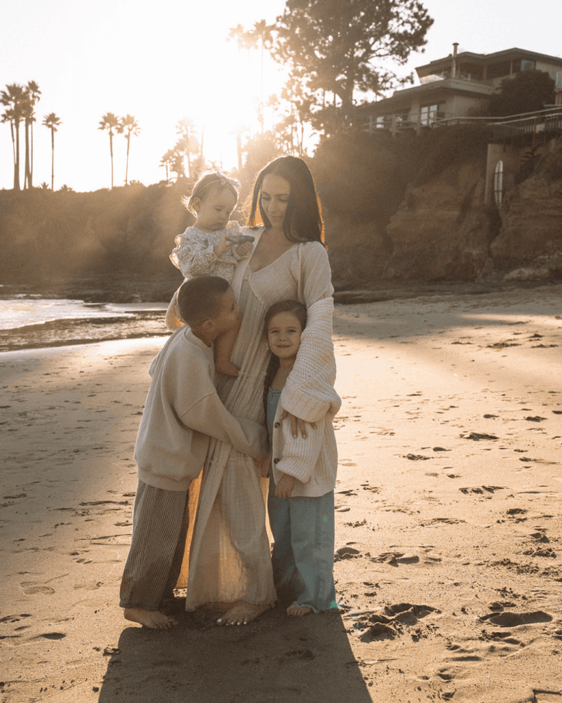 Mother walking along the water with her children during a candid Orange County family photoshoot at the beach.