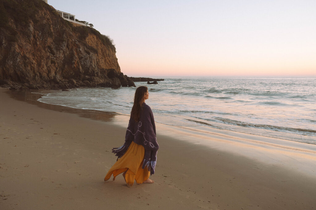 Yoga and wellness business owner walking along the shore during her Laguna Beach branding photos session at Emerald Bay.