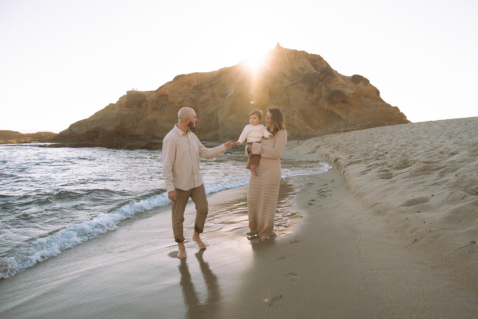 Family walking along the shoreline at Goff Cove in Laguna Beach during sunset, photographed by Maria Alcantara Photography.