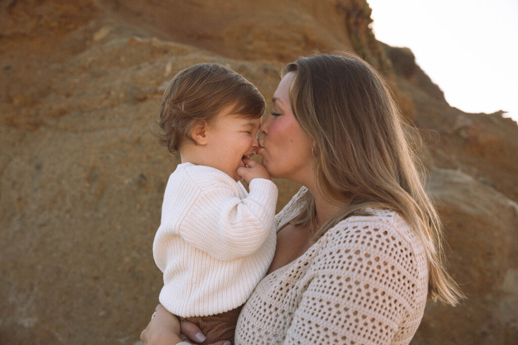 Mother and child sharing a quiet moment against the cliffs of Laguna Beach during a relaxed family photography session in Orange County.