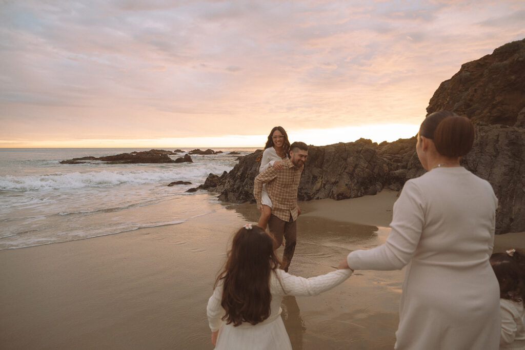 A family laughs and plays together near the rocky coastline at Crescent Bay during a relaxed South Orange County beach session.