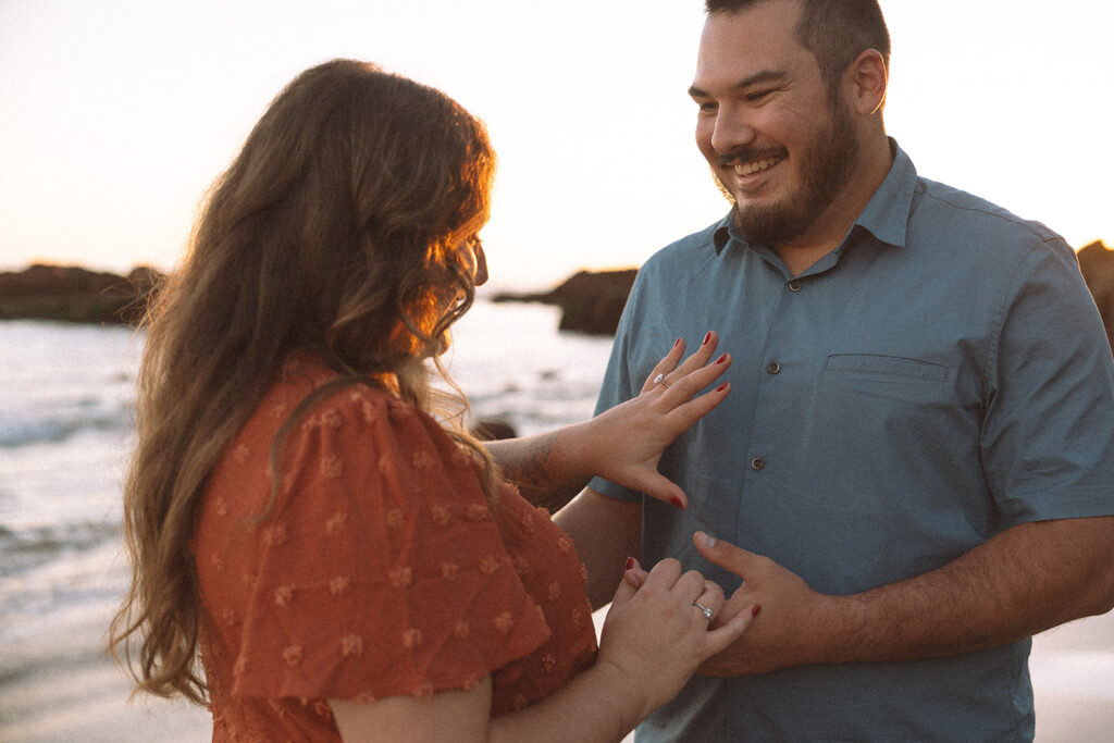 Couple celebrating their engagement in Laguna Beach, sharing a quiet moment after the proposal with the ocean behind them.