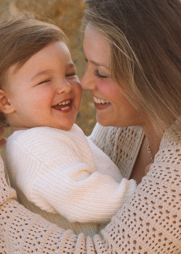 A close-up moment between a parent and child, sharing a laugh in warm evening light.