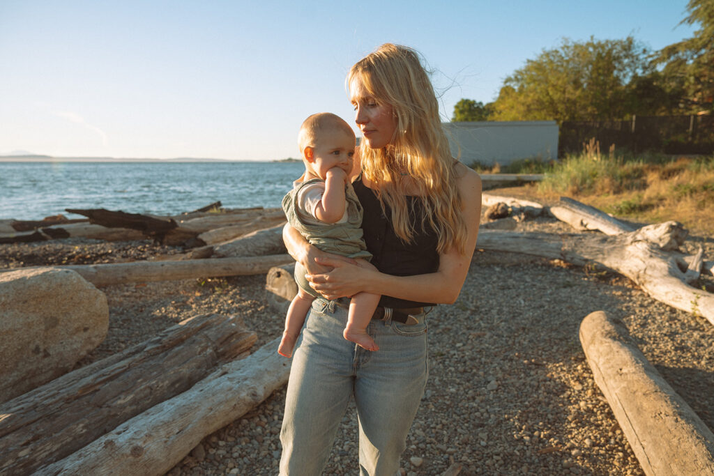 Mom holding baby at waterfront during golden hour. Costa Mesa family photographer.