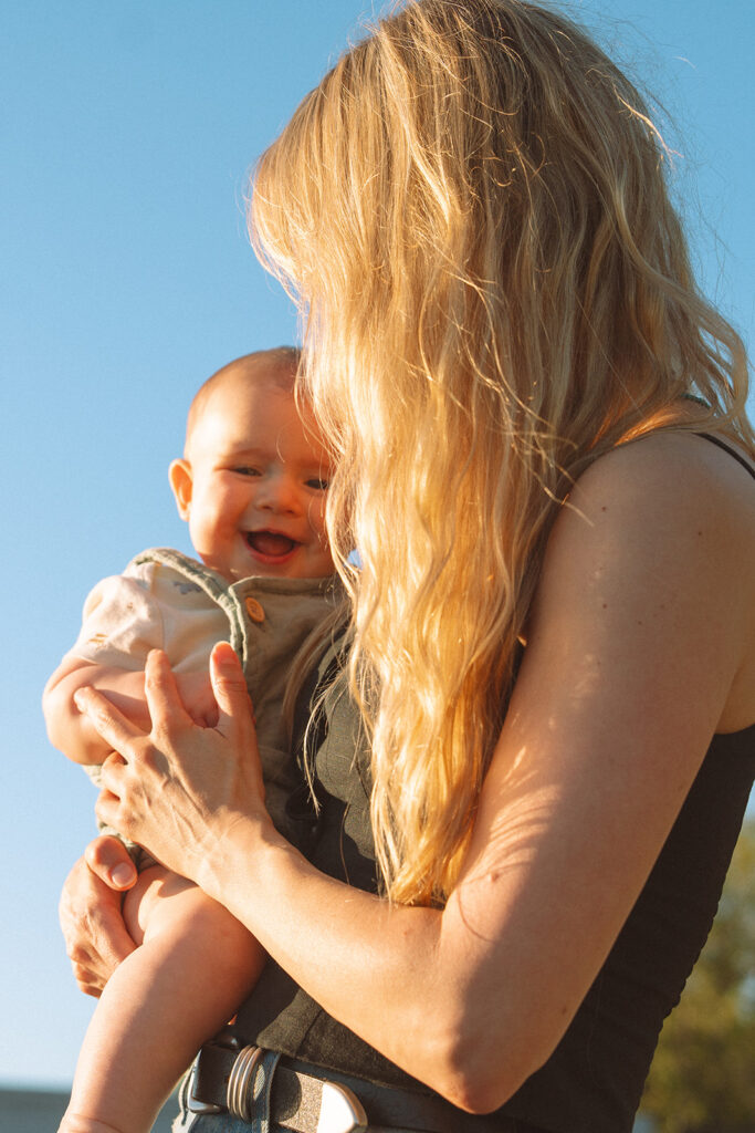 Baby laughing in Mom's arms during family photoshoot.