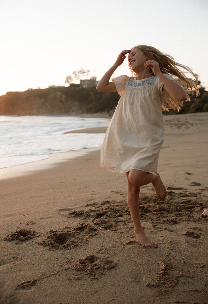little girl spinning on the beach at golden hour in Laguna Beach — documentary family photographer Orange County