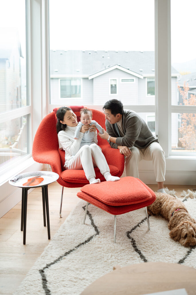 Mother holding newborn in rocking chair with dog, natural light in-home session Orange County
