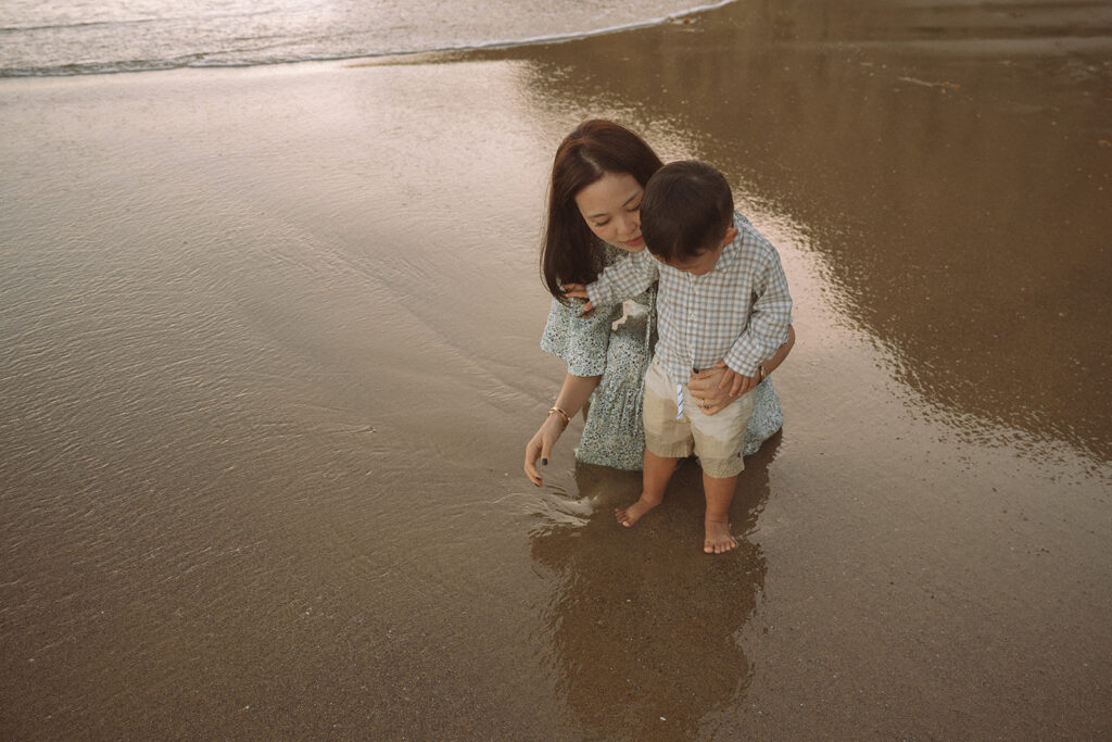 Mom and toddler son playing in the wet sand at golden hour during a Laguna Beach family photography session