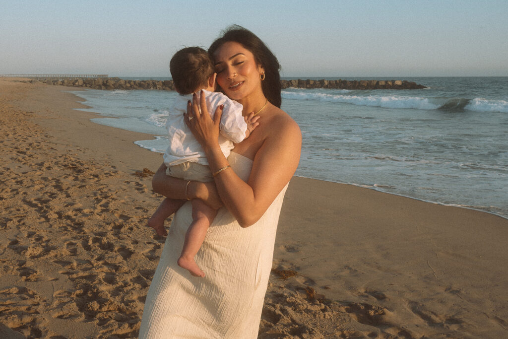 Mom holding baby at sunset at Orange County beach.