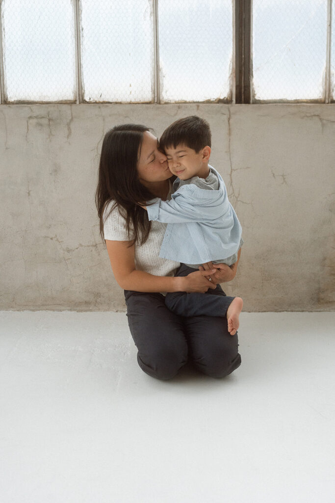 Mother kissing child's cheek while holding them in studio session