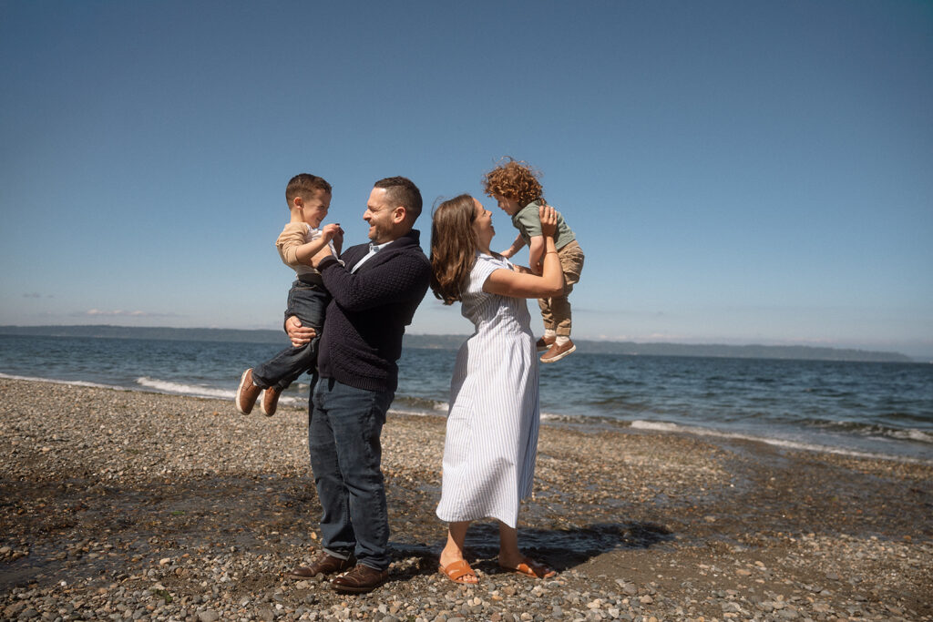 Parents and children playing on beach during playful family photos session