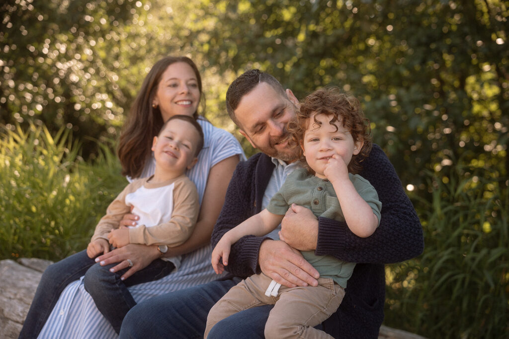 Family of four seated outdoors in garden setting, family photos with natural light