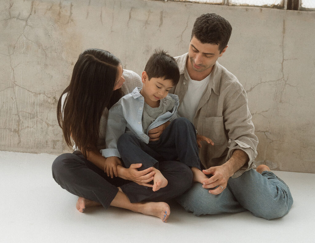 Parents and young child kneeling together in studio, intimate family moment