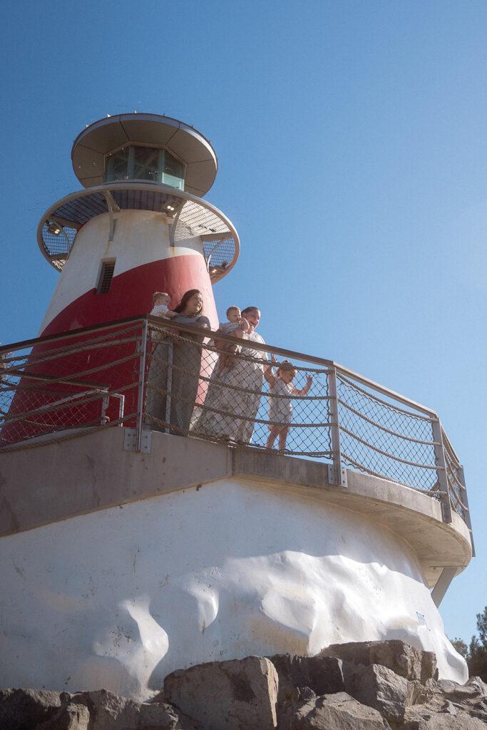 Family of five standing at the top of a lighthouse replica at Marina Park, Newport Beach.