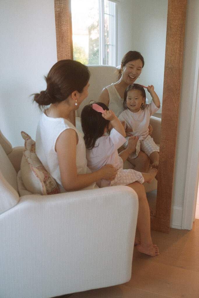 Mother and daughter playing with hairbrushes in candid mirror reflection
