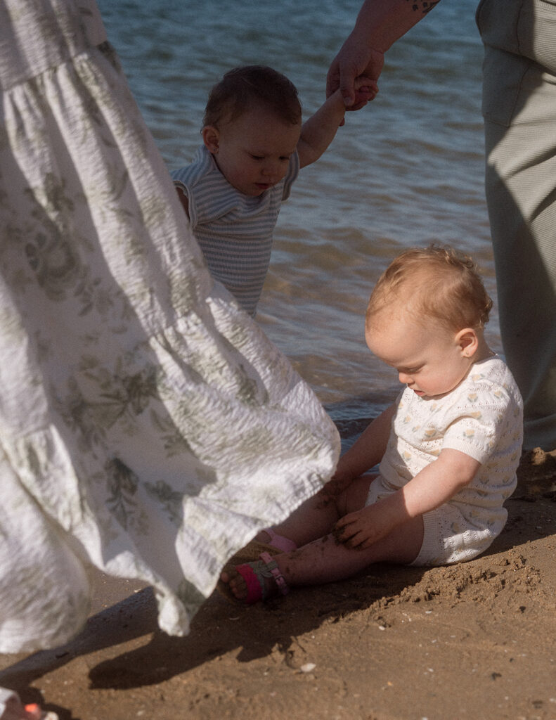 Two toddlers playing together in the sand at an Orange County shoreline.