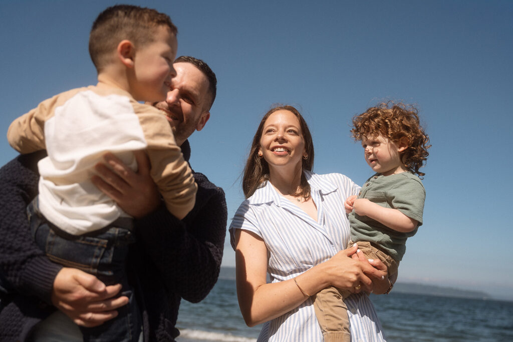 Parents holding up two children on beach