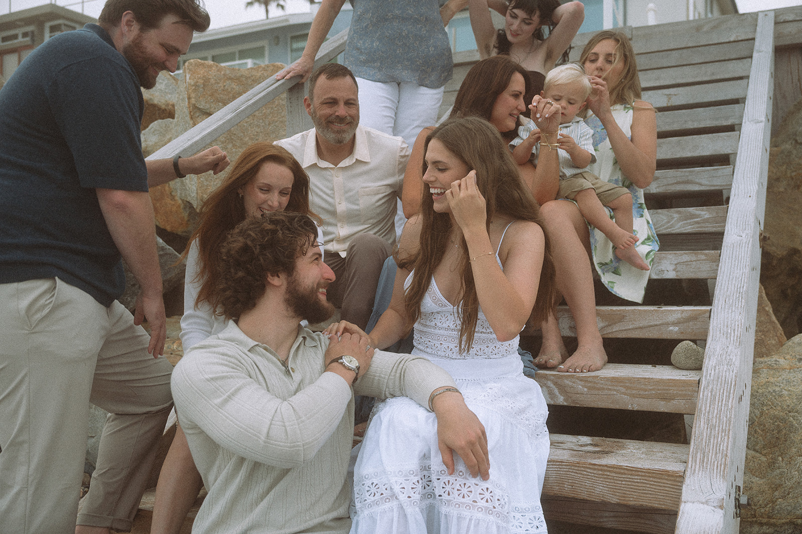 Family of ten laughing together on the stairs at the end of their extended family beach session