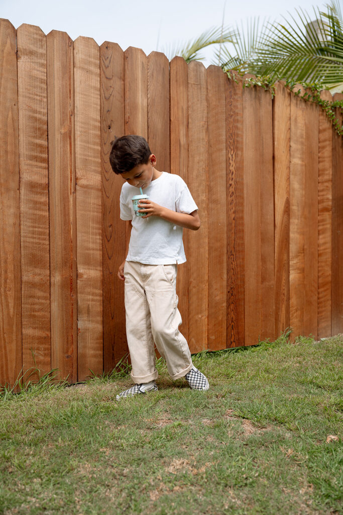 Child standing in backyard holding reusable cup
