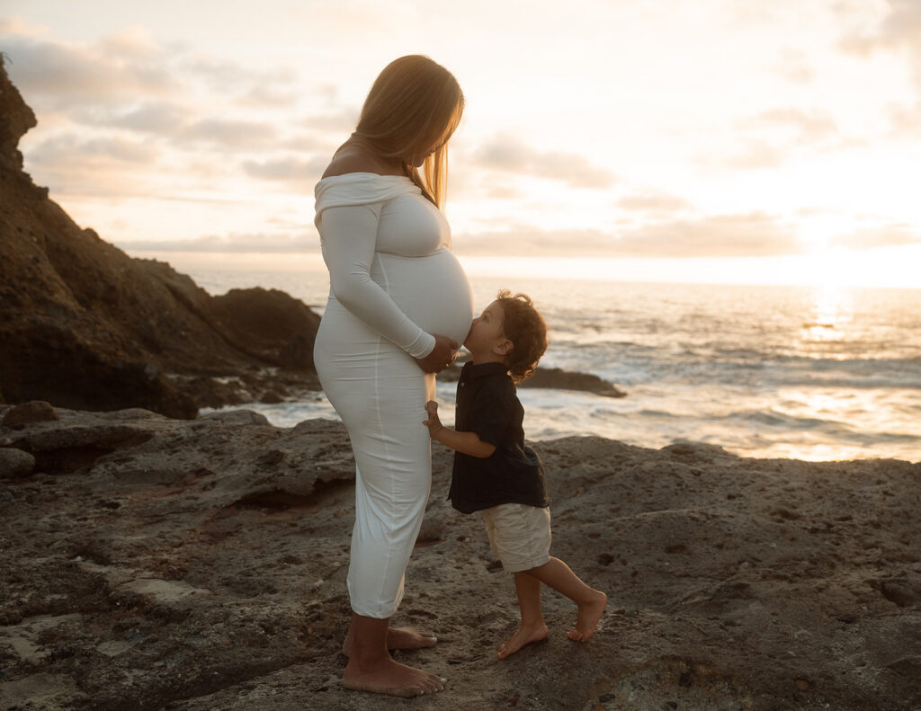 Little boy kissing his mother's pregnant belly at sunset near the Montage in Laguna Beach.